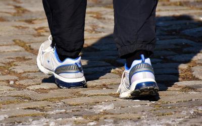Person walking outdoors wearing a pair of comfortable walking shoes.