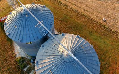 Two large grain bins next to a recently harvested field of soybeans.