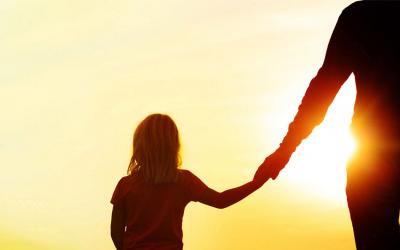 Silhoutte of mother and daughter holding hands at sunset.