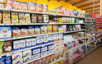 Variety of flour types on display in a grocery aisle.