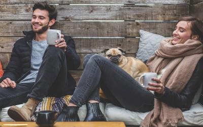 A couple having a conversation while drinking coffee with their dog.