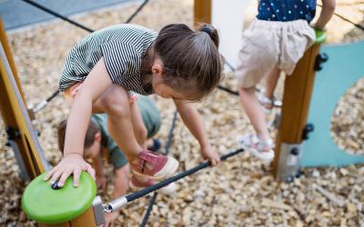 Group of young children climbing on a playground obstacle course.
