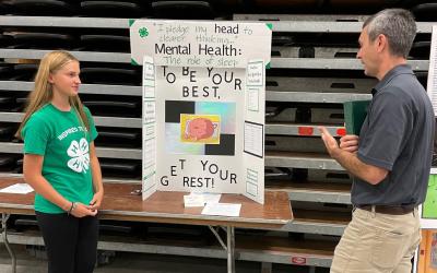 4-H member Olivia Miller discussing her mental health presentation with South Dakota 4-H Program Director Tim Tanner.