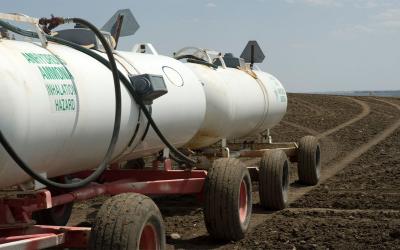 Tanks of anhydrous ammonia being pulled to a field for fertilizer application.