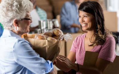 Woman delivering a bag food donations to a food bank manager.