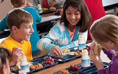Group of children eating school lunch in a cafeteria.
