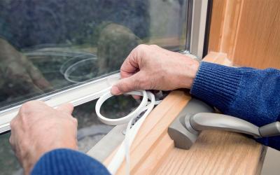 Installing weather stripping around a window.