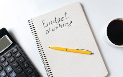Calculator, pen, and notebook with "Budget Planning" written on it.