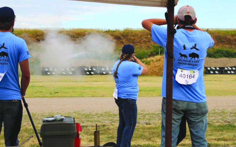 99-4-H-Shooting-Sports 4-H, Shooting Sports, Muzzleloading gun, Adolescent girl shoting a muzzleloading gun while 2 adolescent males watch