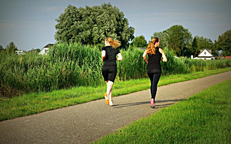 Two females jogging on trail on a summer day