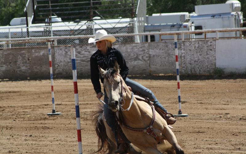 young cowgirl running a horse through the pole bending pattern