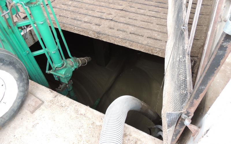 A slatted floor with an open area. A hose is running into the open area.