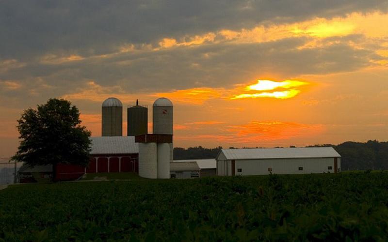 A family farm with the sun setting in the background.
