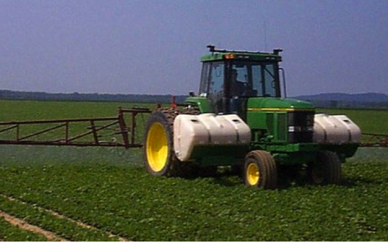 a tractor in a field spraying soybeans