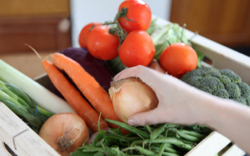 a hand pick an onion from a box of vegetables