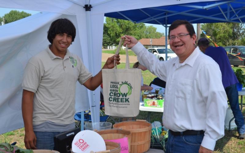 A young native american man handing a customer a canvas bag.