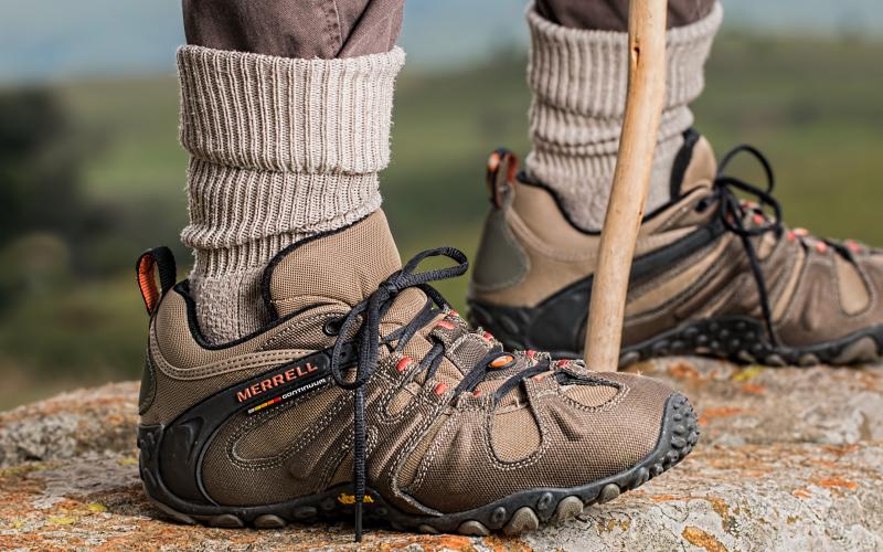 An older man wearing hiking boots standing on a rock.