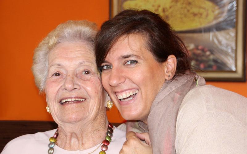 Older woman and her granddaughter smiling while they pose for a picture.