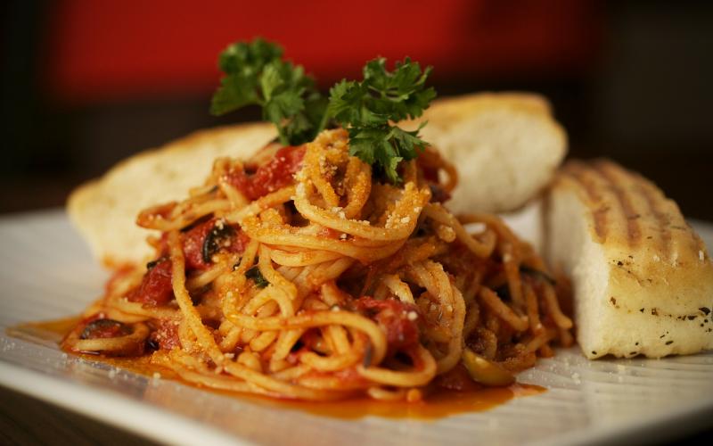 A plate of spaghetti with meat sauce and two slices of garlic bread.