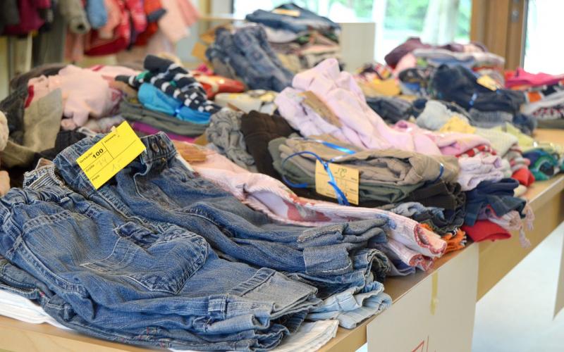 Stacks of children's clothing ready for donation.