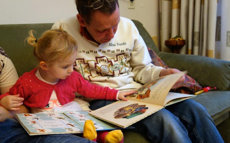 A father reading a book with his young daughter.