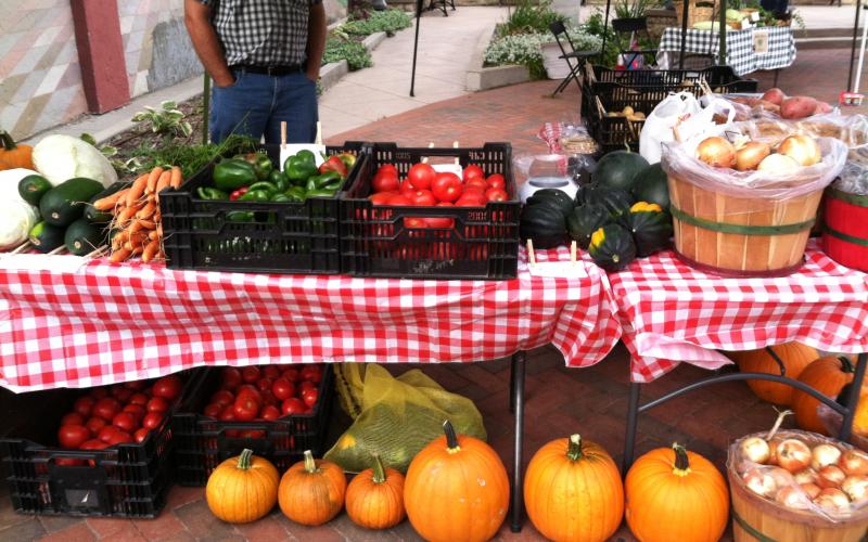 A table at a farmers market filled with fresh vegetable displays.