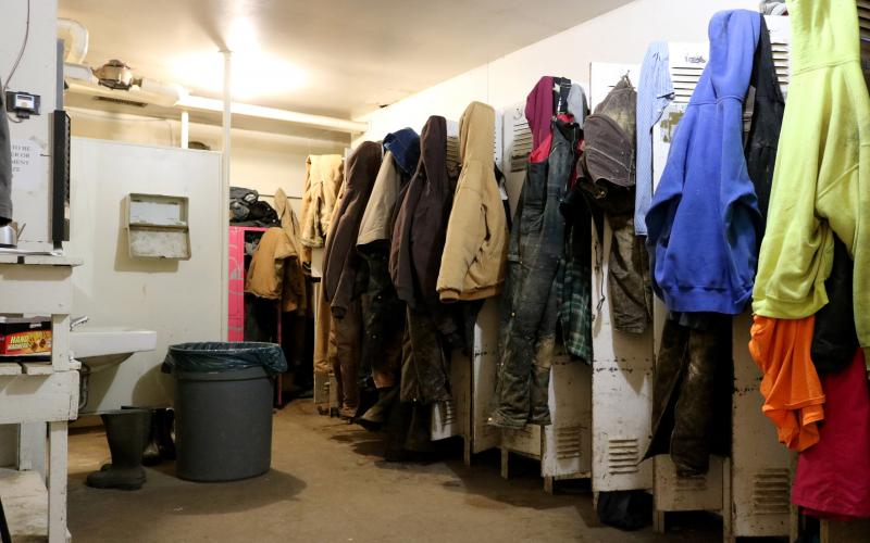 row of lockers with several employee jackets, hats, and clothing hanging outside.