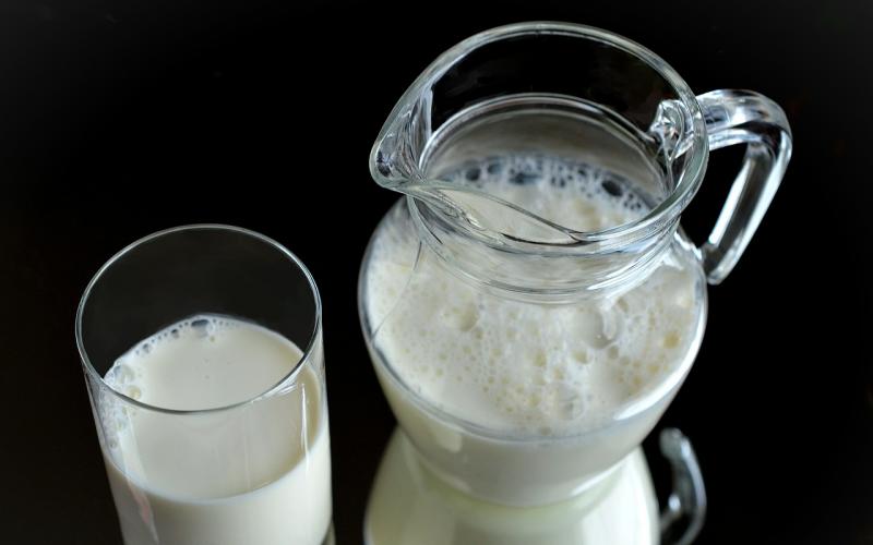 A glass of milk and a milk pitcher.