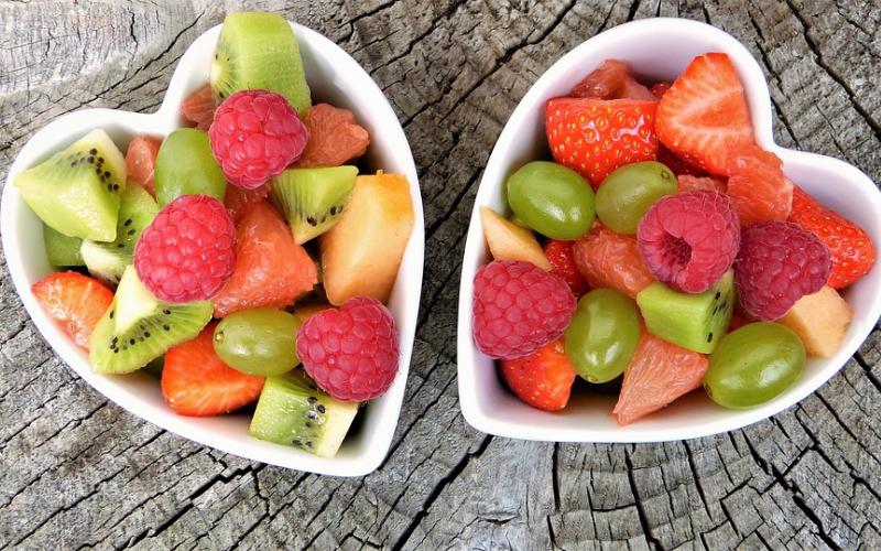 two heart-shaped bowls filled with mixed fruit