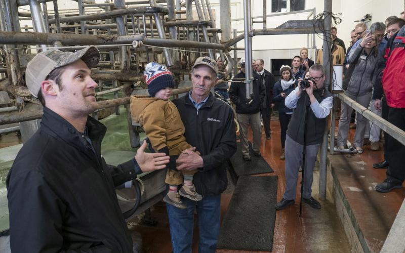 male dairy worker greeting a crowd of people inside a dairy processing facility
