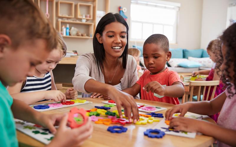 a young woman leading a group of young children in a learning activity