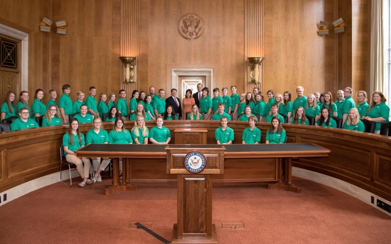 large group of 4-H youth posing for a photo with U.S. government officials inside a governmental chamber