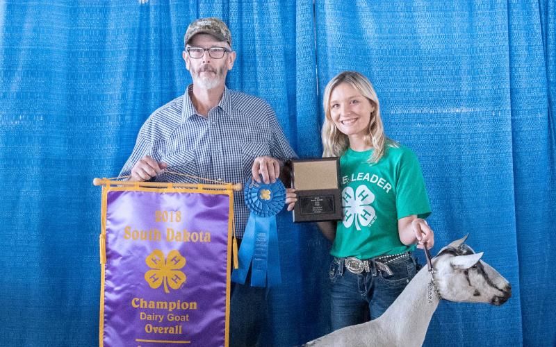 father and daughter holding numerous 4-H awards with their dairy goat