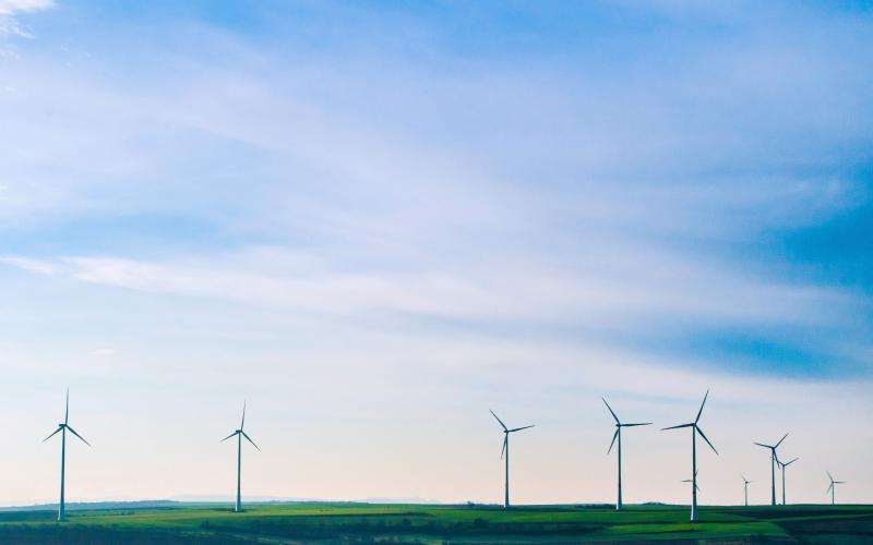 several white wind turbines towering above agricultural production land