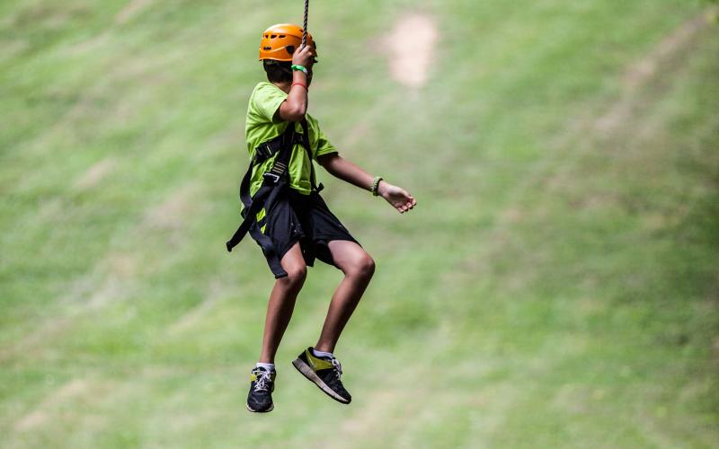 a young male swinging down a zip line