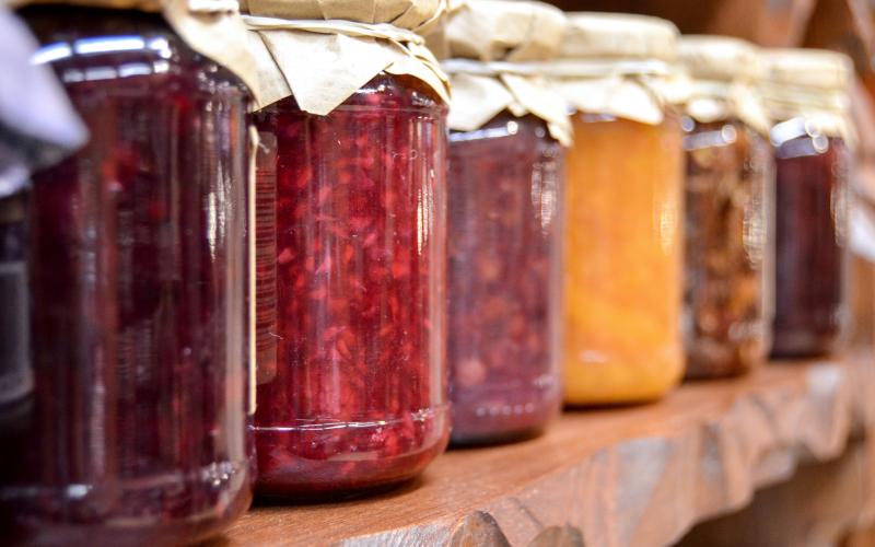 cans of various jams and jellies on a shelf