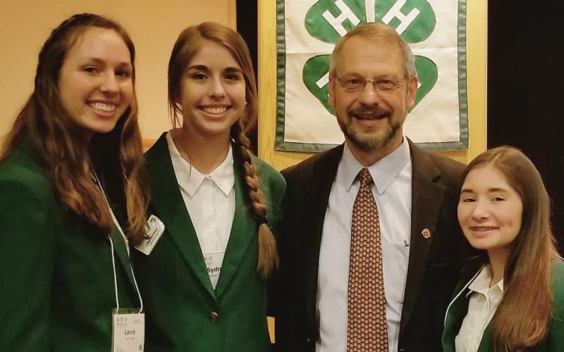 three female 4-H youth standing with and older adult male official