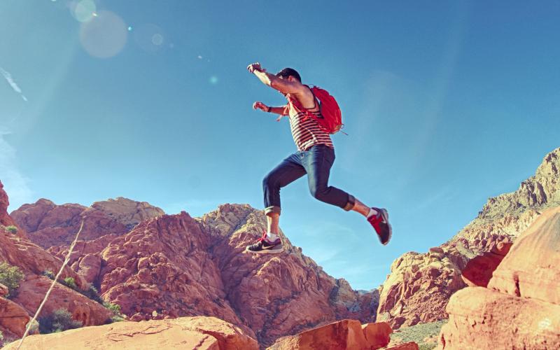 male youth bounding over desert rock formations