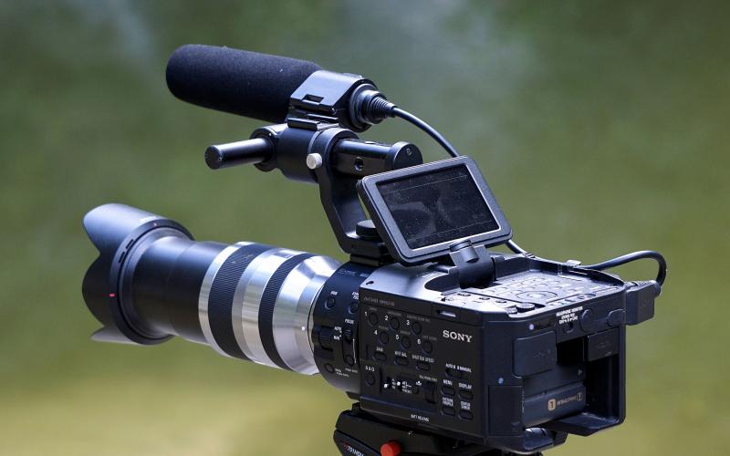 a digital camera with an onboard boom microphone on a tripod.