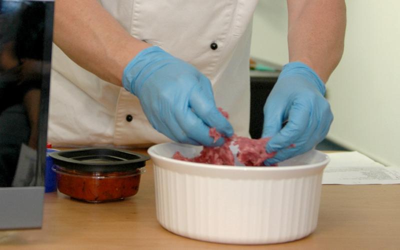 man with rubber gloves inspecting cell-based food product