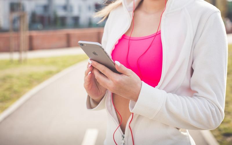 young woman in jogging outfit reading information on her phone