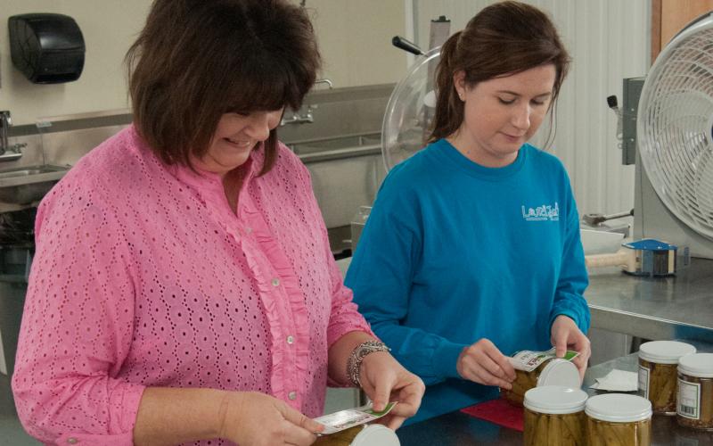 a mother and daughter putting labels on home-canned food products. Photo by Stephen Ausmus, USDA