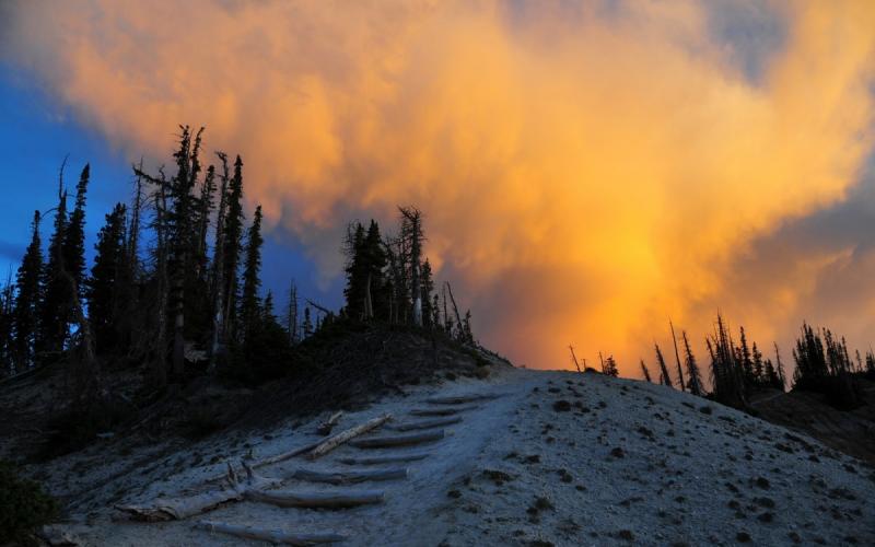 wildfire smoke rising in the distance over a snowy hill
