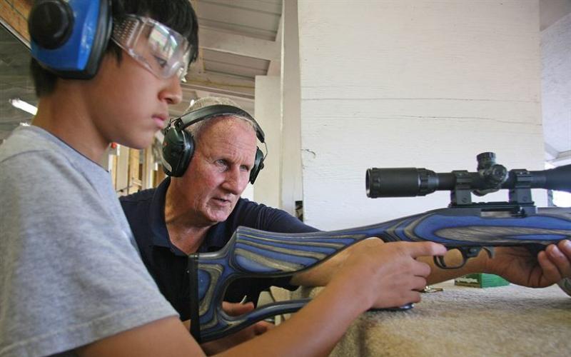 4-H youth with shooting instructor preparing to fire a rifle