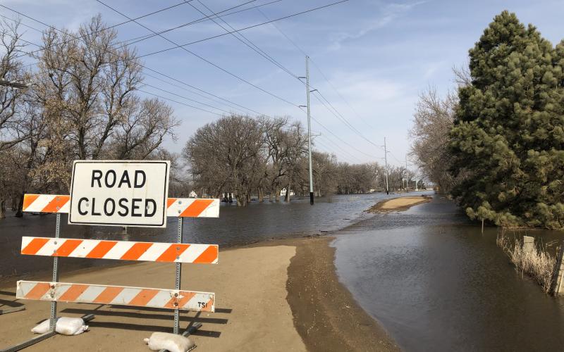 road closed sign in front of a flooded road
