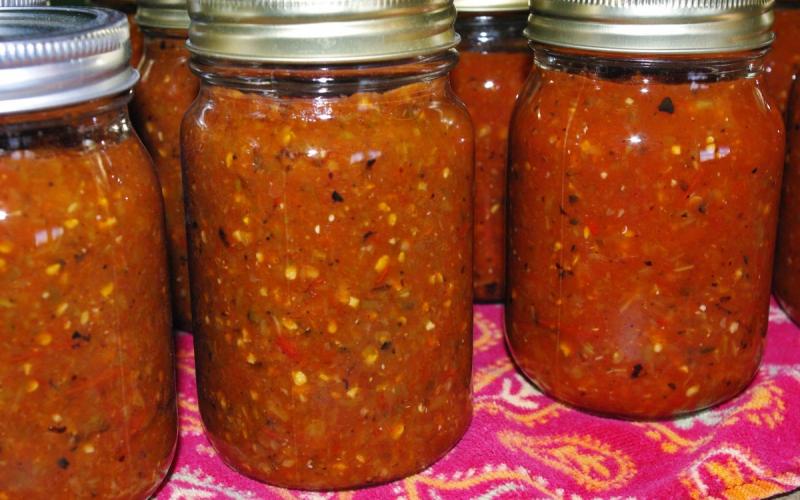 Several cans of homemade salsa sitting on a table.