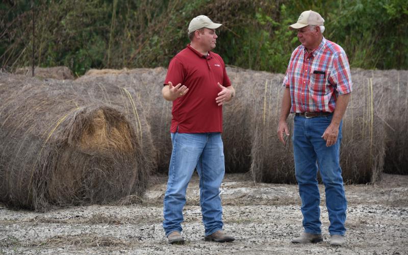 rancher and employee discussing an issue near hay bales