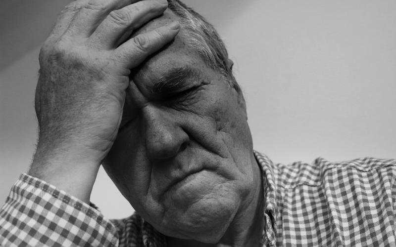an older male adult holding his forehead
