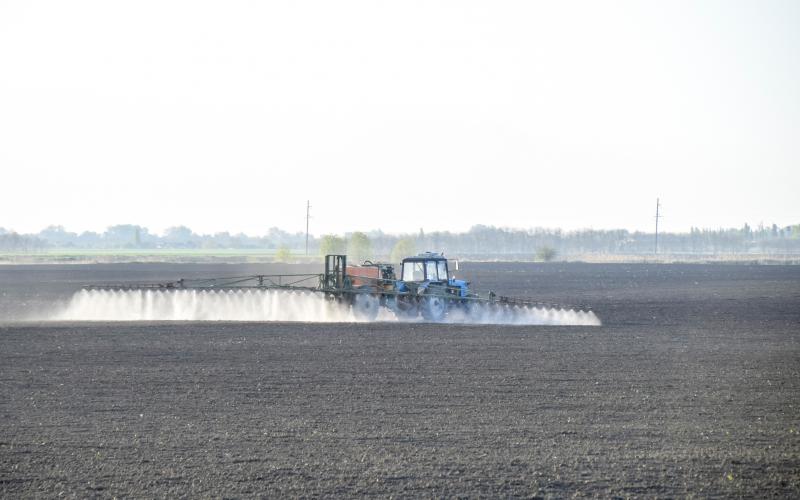 A sprayer applying pre-emergent pesticide to a bare field.