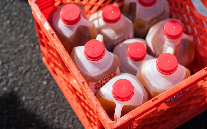 Several sealed cartons of apple cider in a red milk crate.